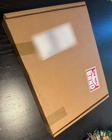 The flat shipping box, label blurred, with a Do Not Bend sticker