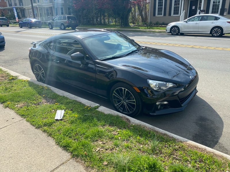 Phone photo of a black coupe parked at a curb, seen from the front passenger side