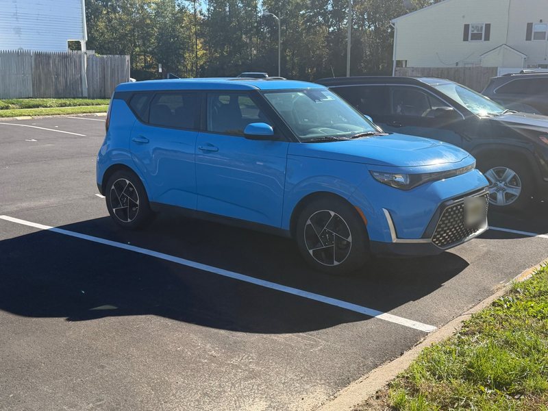 Phone photo of the crossover's driver's side, showing its wheels, plate blurred